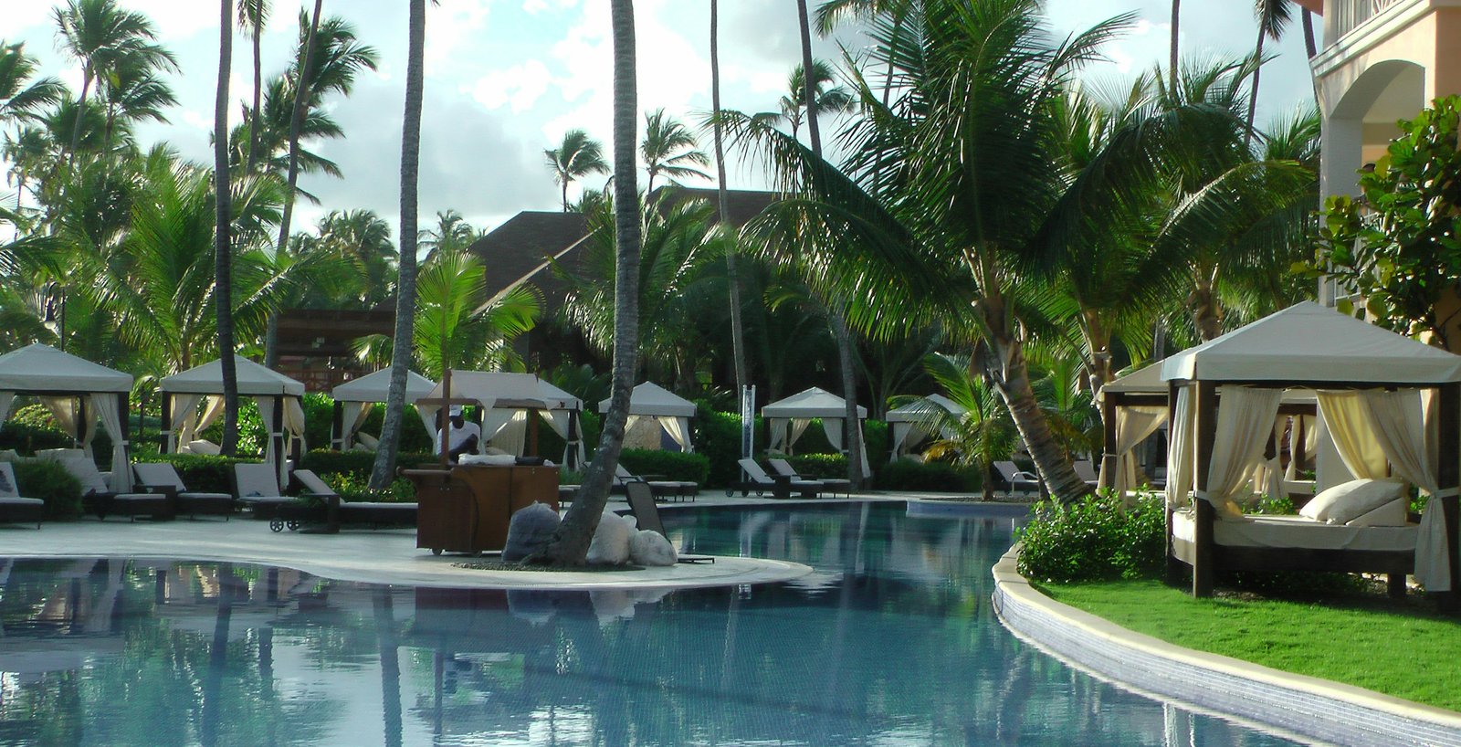 Palm-lined resort pool with shaded cabanas.